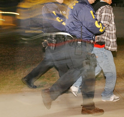 Immigration and Customs Enforcement (ICE) officers arrest a suspect during a pre-dawn raid in Santa Ana, Calif., Wednesday, Jan. 17, 2007. (AP Photo/Mark Avery)
