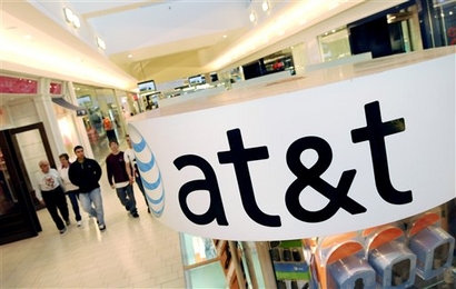 In this file photo made Tuesday, Oct. 20, 2009, people walk through the Northshore Mall beyond near an AT&T kiosk, in Peabody, Mass. AT&T said
