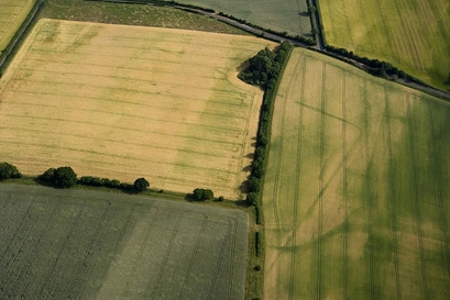 One of the rounded corners of the Roman Camp and an entrance can be seen as a narrow green line in the field on the right hand side of the photograph. This ditch can then be traced as a faint line in to the adjoining yellow field to the left and forming another corner. (Photo Courtesy of English Heritage)