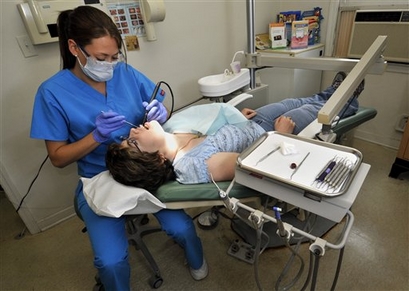 Dental hygienist Sarah Reilly cleans the teeth of Medicaid patient Rachel Bogartz at the dental office of Dr. Jonathan Knapp in Bethel, Conn., Monday, July 20, 2009. Connecticut and other cast strapped states are considering cuts to Medicaid targeting benefits considered to be optional by the federal government, such as dental coverage for adults. (AP Photo/Jessica Hill)
