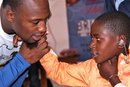 In a March 21, 2011, photo provided by the Starkey Foundation, San Francisco 49ers ' Vernon Davis helps distribute hearing aids to an unidentified child in Runhengeri, Rwanda. Davis regularly thinks about the NFL lockout, wondering when his football routine might return to normal. For now, he is going about his usual workout schedule and preparing like this were any other year. He and his younger brother, Dolphins cornerback Vontae Davis , spent 10 days helping distribute hearing aids in Uganda and Rwanda.