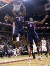Atlanta Hawks ' Josh Powell (12) hangs from the hoop after scoring near teammate Josh Smith (5) and Toronto Raptors ' Amir Johson (partially obscured) during first-half NBA basketball game action in Toronto, Sunday, Nov. 28, 2010.