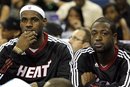 Miami Heat forward LeBron James , left, and guard Dwyane Wade watch from the bench during the first half of an NBA preseason basketball game against the New Orleans Hornets in New Orleans, Wednesday, Oct. 13, 2010.