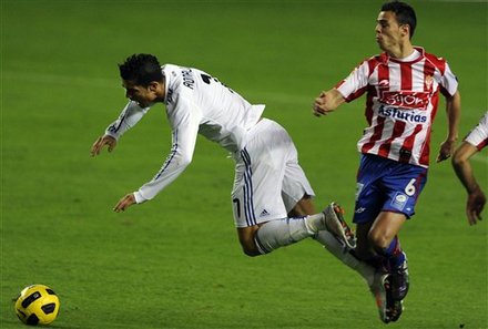 Real Madrid's Cristiano Ronaldo From Portugal, Left, Vies For The Ball With Sporting De Gijon's Carmelo Gonzalez, Left,